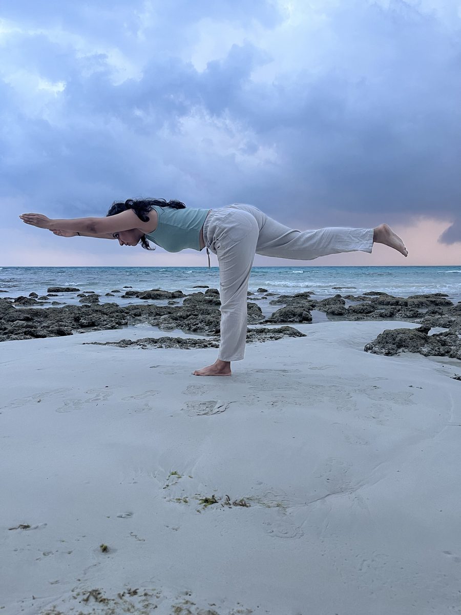Prajakta Gogate performing Warrior III posture (Virabhadrasana C) on the beach, Certified Yoga Instructor